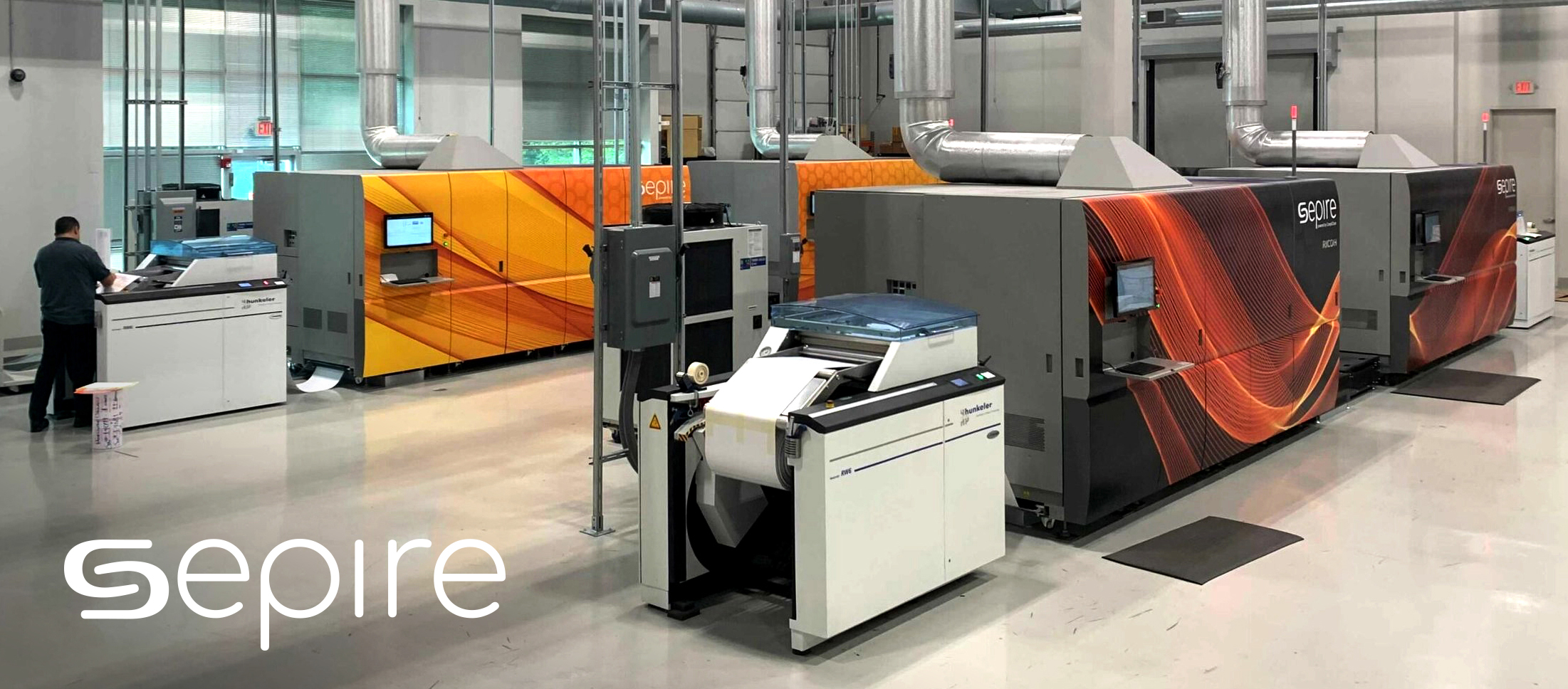 A photo of the production floor showcasing the RICOH Pro VC70000 production inkjet printer wrapped in colorful branded Sepire graphics.
